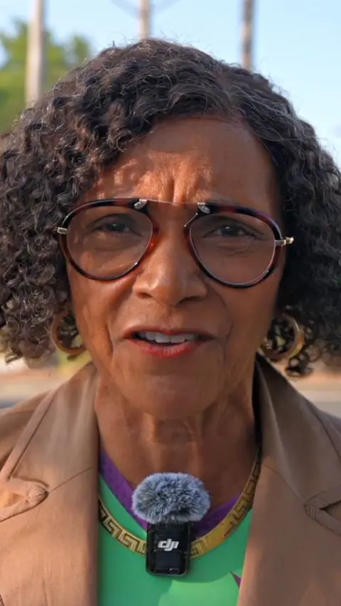 A woman looks into the camera.