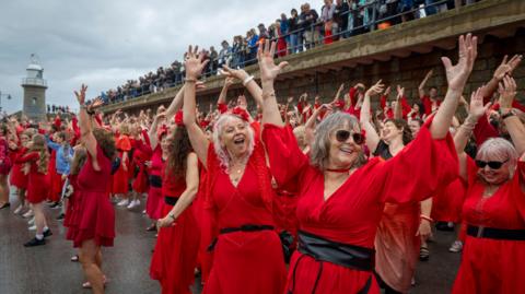 Hundreds of Kate Bush fans came together today wearing red floaty dresses on Folkestone's Harbour Arm to dance to her most iconic song, Wuthering Heights on the 20th of July 2025 in Folkestone, United Kingdom. 
