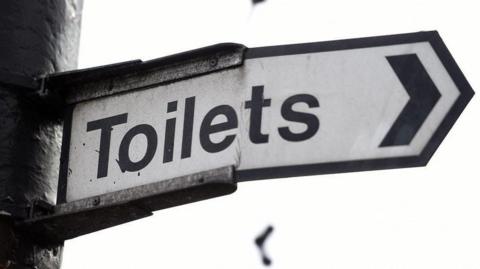 A sign with "Toilets in black writing.