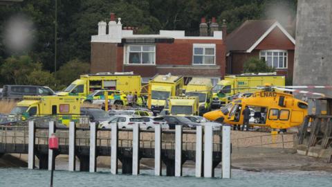 Numerous ambulances and a coastguard helicopter at the scene on the water's edge