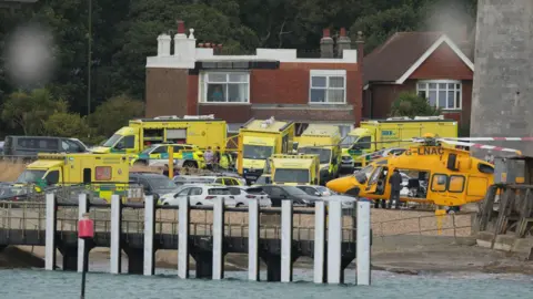 Numerous ambulances and a coastguard helicopter at the scene on the water's edge