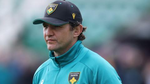 Phil Dowson, wearing a baseball cap, watching Northampton Saints