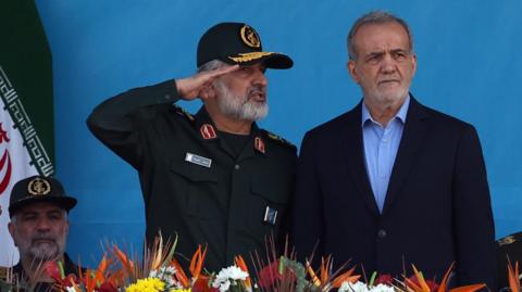 Iranian President Masoud Pezeshkian (R) and the commander of the Islamic Revolution Guard Corps' Aerospace Force, Amir Ali Hajizadeh (L), attend a military parade in Tehran, Iran (21 September 2024)