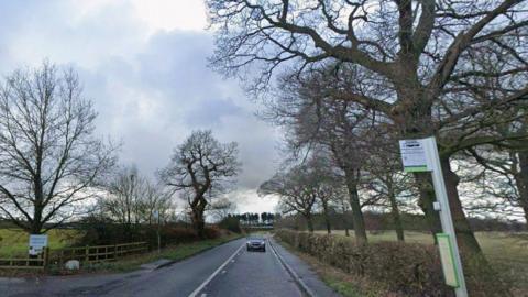 Road with a bus stop to the right of the image