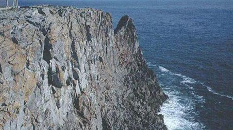 A picture of a rough cliff edge, alongside the sea