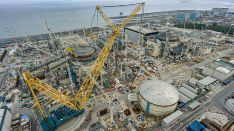 A giant yellow crane is in pictured in a huge construction site by the sea.