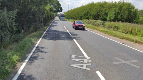 A section of the A47 road near King's Lynn with grass and hedges either side and traffic travelling along the road. 