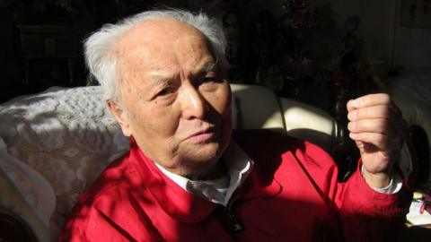 Li Rui, seen before his death, wears a red jacket and a white collared shirt