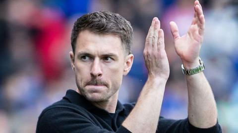 Aaron Ramsey in dark sweater applauds