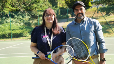A man and a woman pictures standing on a tennis court both holding rackets