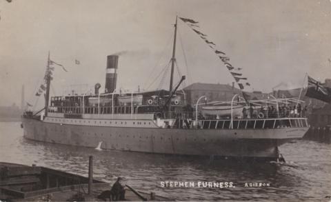 A sepia image of the boat HMS Stephen Furness, cruising along a body of water. Bunting strung across and a Union Jack flag waving from the front of the ship.