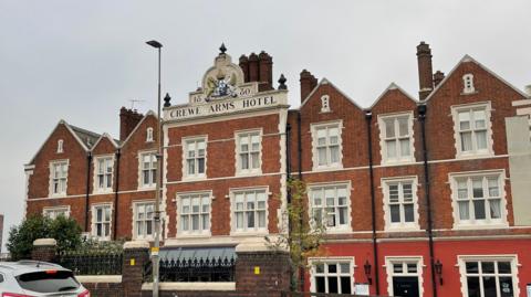 An image of Crewe Arms Hotel, a large red brick building.