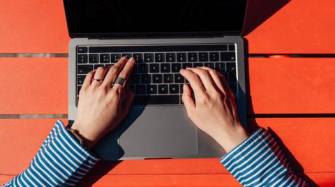 A woman typing on a laptop keyboard