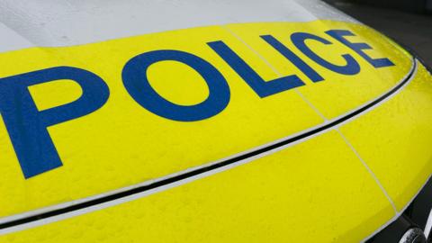 A bright yellow bonnet on a police car with the word Police on it in blue.