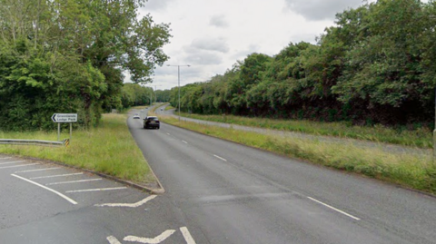 Image of the Warwick Highway which has two lanes on each side of the road. There is grass in between the different directions and trees lining the outside of the road. 