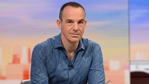 Martin Lewis sat in a TV studio, wearing a dark blue shirt