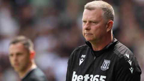 Mark Robins in his back Stoke City training top looks on from the touchline during a game