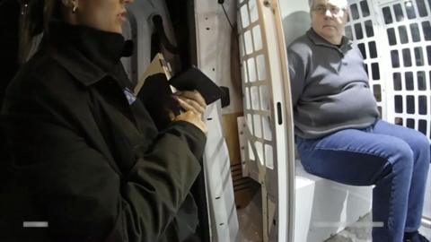 man sitting in the back of a police van being read his rights