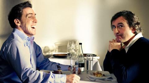 Rob Brydon and Steve Coogan sit at a dinner table together