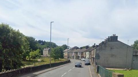 A Google Street View screenshot of the houses at Hall Park View in Workington, which is a row of terraced houses along Hall Brow and opposite Hall Park.