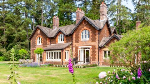 External view of The Gardens House. It is a large building with ornate brick work and lots of chimeys. 