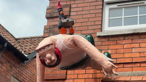 A scarecrow of Wallace and Feathers McGraw from Wallace and Gromit dangles from a property