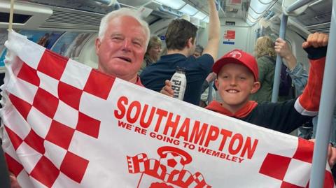 older man and younger boy hold saints flag