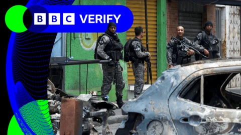 Armed police officers in front of burnt out cars