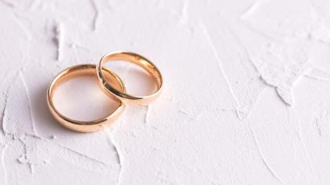 Two gold wedding rings on a white background.