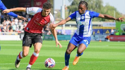 Lincoln's Bailey Cadamarteri battles for possession with Wigan's Silko Thomas. 