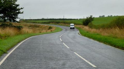 A winding road in south west Scotland with a van in the distance wending its way through green countryside