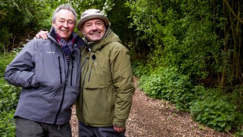 Mortimer & Whitehouse posing for a picture in waterproof clothing in a forrest