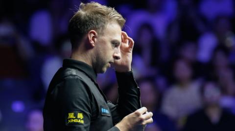Judd Trump holds his left hand to his head at the Wuhan Open