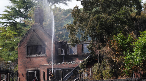 Firefighters spraying water onto the burnt out remains of a house following a huge blaze in Stourbridge, in the West Midlands, which forced some people to flee after it started tearing through homes. Fire crews are making progress tackling huge blazes in the West Midlands that led to thousands of 999 calls and caused "extensive" devastation.