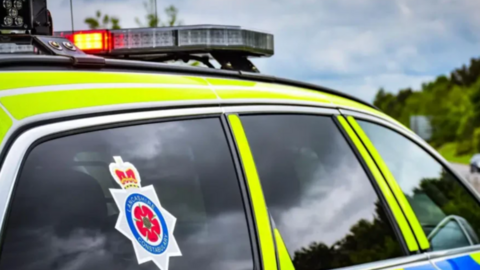 Close-up of a Lancashire Police car with the force emblem in the rear passenger window