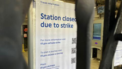 Shutters closed at Kentish Town Station during a Rail and Tube Strike. There is a poster behind the closed barrier saying 'Station closed due to strike'.