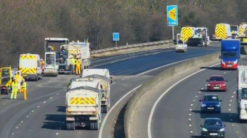 Highways vehicles on the M1 including vans, lorries and rollers, carrying out emergency resurfacing work. 