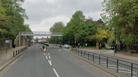 Durham Road at Sunderland College's Bede campus. It has three lanes and the middle one is for turning right into the college entrance. The road is surrounded by trees and has a pedestrian over pass. One white car is travelling past the college.