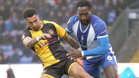 Newport's Courtney Baker-Richardson battles for the ball with Oldham's Manny Monthe