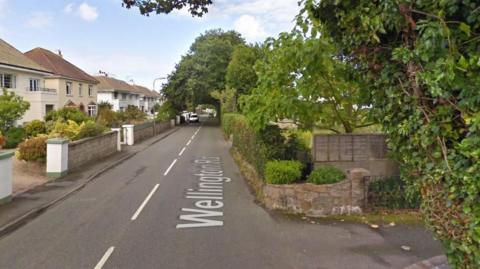 Google Street View image of Wellington Road in St Helier. Houses are on both sides of the roads. Several trees in full bloom are also dotted along the road.