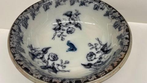 A professional image of a white serving bowl with an intricate dark blue floral and bird pattern
