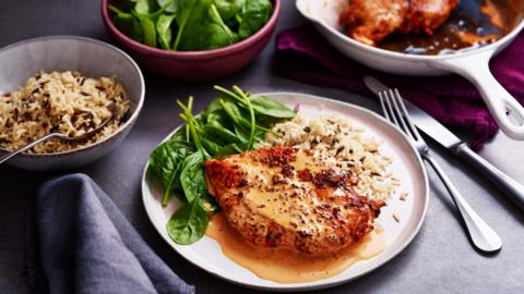 A plate of creamy paprika chicken with rice and spinach.