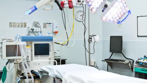 An empty bed in a hospital operating theatre surrounded by hospital equipment