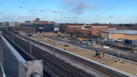 The area just outside of Darlington train station. There are multiple sets of train tracks and construction work on the land to the side.