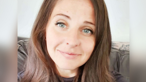 Laura-Jane Seaman smiling and looking directly at the camera, with long brown hair and blue eyes.