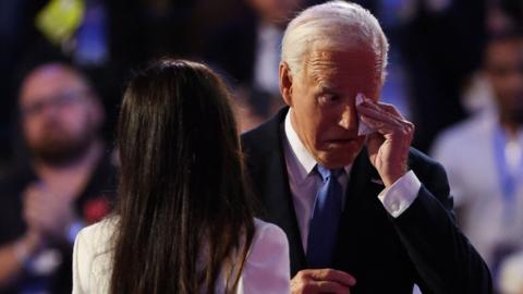 US President Biden wipes his eyes with a tissue