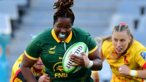 Chumisa Qawe of South Africa Women runs away from two defenders with the ball in hand during a rugby game