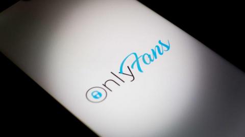 OnlyFans logo displayed on a smartphone screen in silhouette