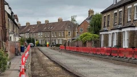Barriers and cones lined up a road where a resurfacing work is being done.