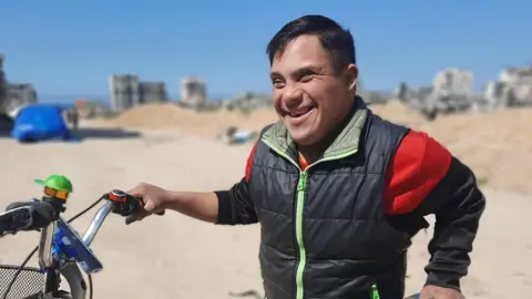Ahmed al Madhoun smiles as he holds his bike. 